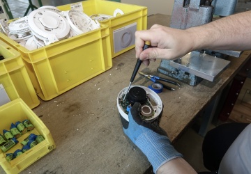 Detailaufnahme beim Zerlegen - es werden gerade Schrauben entfernt, die das Plastikgehäuse mit der Platine verbinden