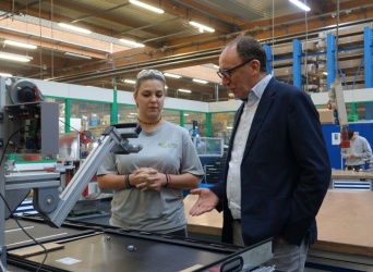 BM Rauch und eine Arbeiterin stehen vor einer Maschine und blicken auf ein Werkstück