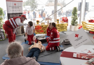 Mitarbeiter des Roten Kreuzes zeigen wie man Herzdruckmassage macht