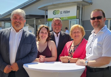 Gäste gemeinsam am Foto wie sie bei einem Stehtisch stehen und in die Kamera lächeln.