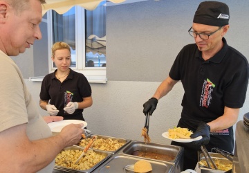 Der Caterer richtet gerade einen Burger für einen Gast an.