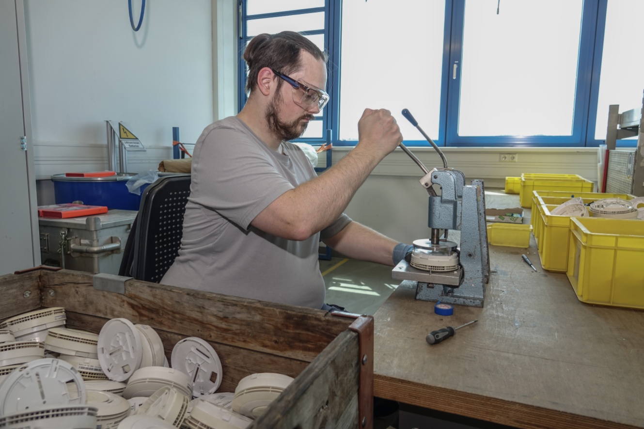 Mitarbeiter bei der Zerlegung eines Rauchwarnmelders