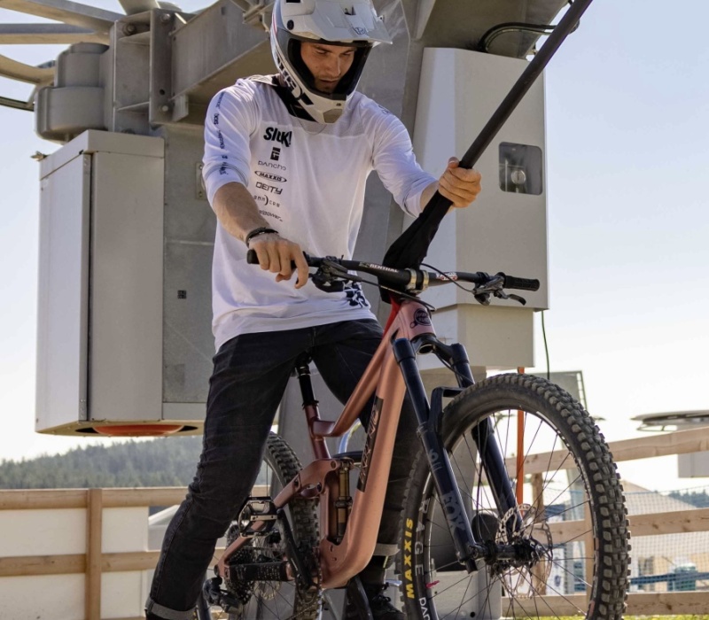 Mountainbiker mit Helm hängt sich an Schleppstange mit seinem Mountainbike.