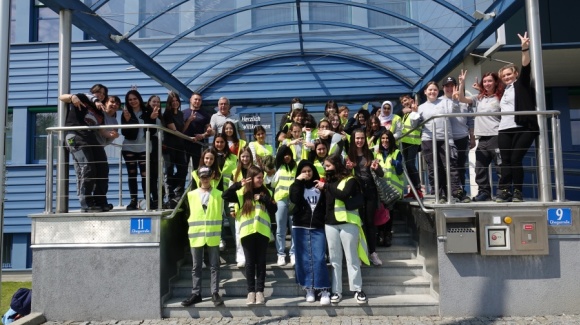 Gruppenfoto der Mitarbeiter*innen und Mädchen in Schutzwesten vor dem Haupteingang der GW