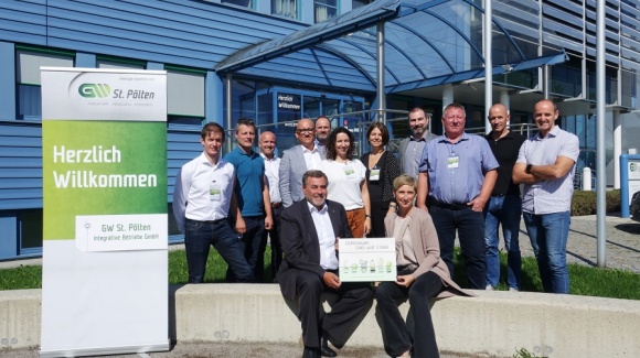 Gruppenfoto der Besucher*innen vor dem GW Gebäude, daneben ein RollUp mit "Herzlich Willkommen"