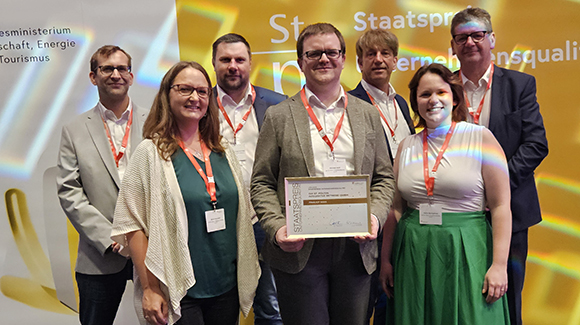 Auf dem Foto sehen Sie 7 Vertreter*innen der GW St. Pölten bei der Preisverleihung mit dem Zertifikat "Finalist 2025" in der Hand.