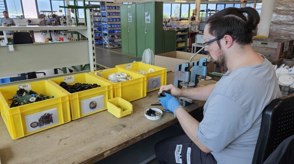 Ein Mitarbeiter auf seinem Arbeitsplatz beim Zerlegen eines Rauchwarnmelders