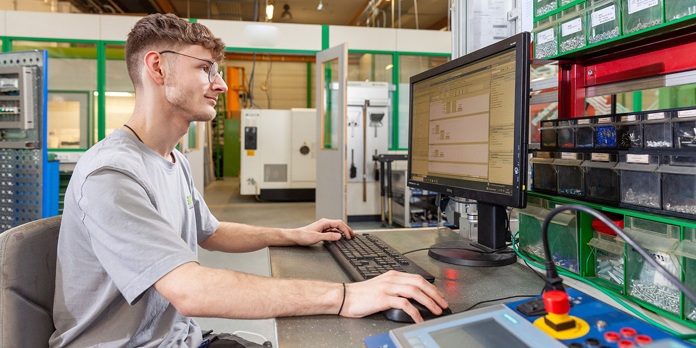 Junger Mann in blauen Shirt sitzt vor Computer, auf dem Bildschirm sieht man ein 3D-Visualisierungsprogramm.