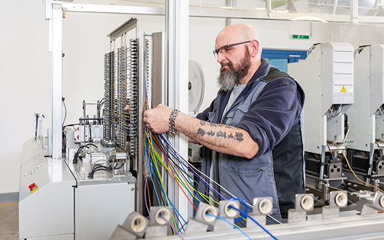 Ein Mann steht konzentriert vor einer großen Kabel-Ansammlung und arbeitet.